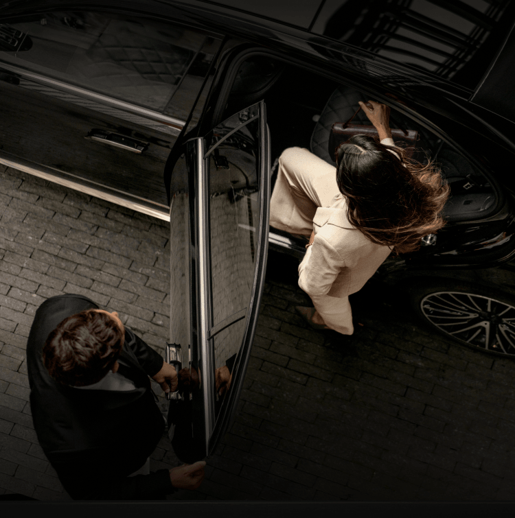 A man holding a car's door open while a woman enters it